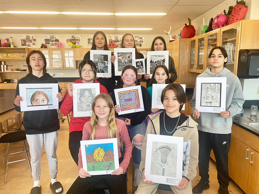 Image of students posing with art work. 