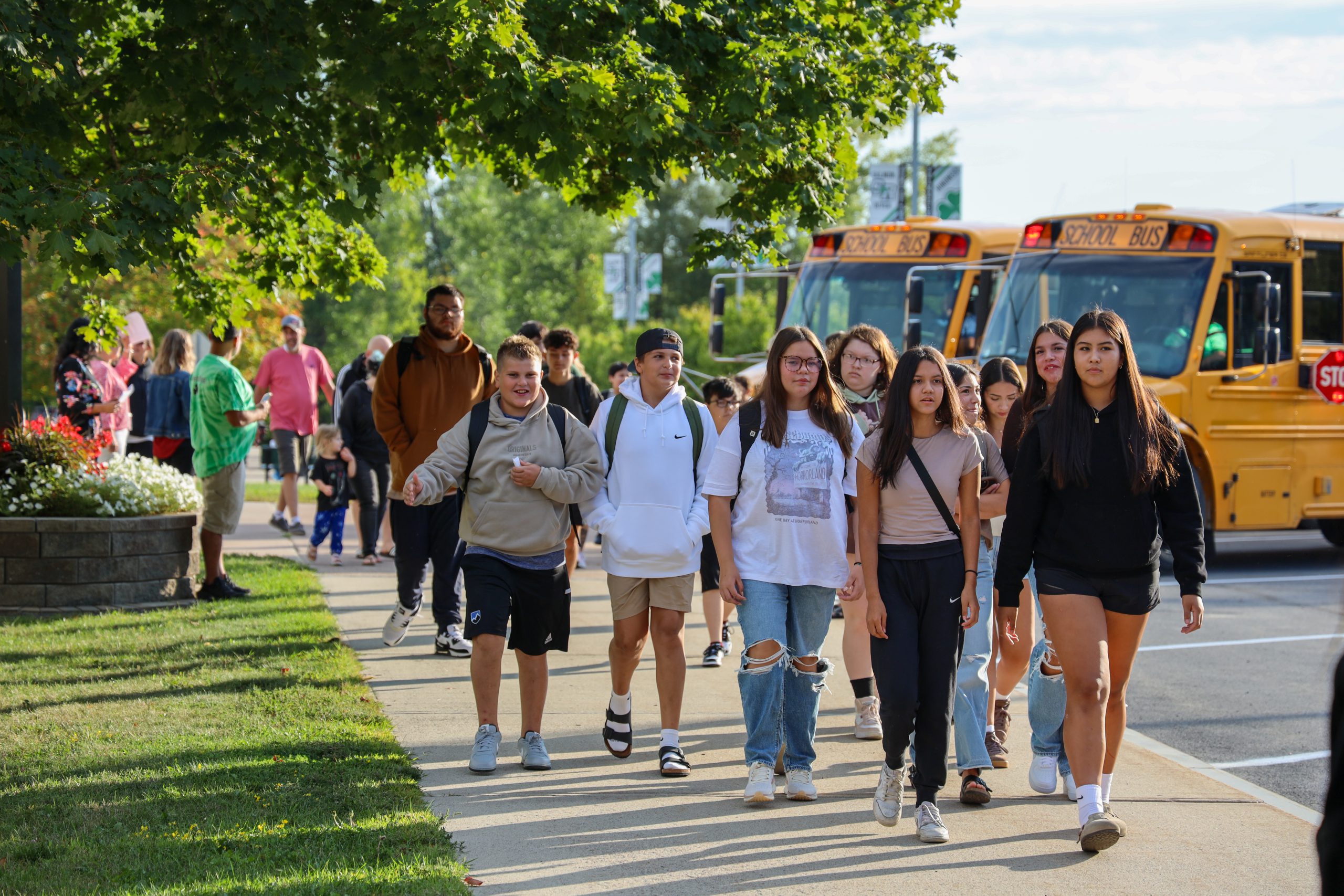 A group of students walking near parked school buses