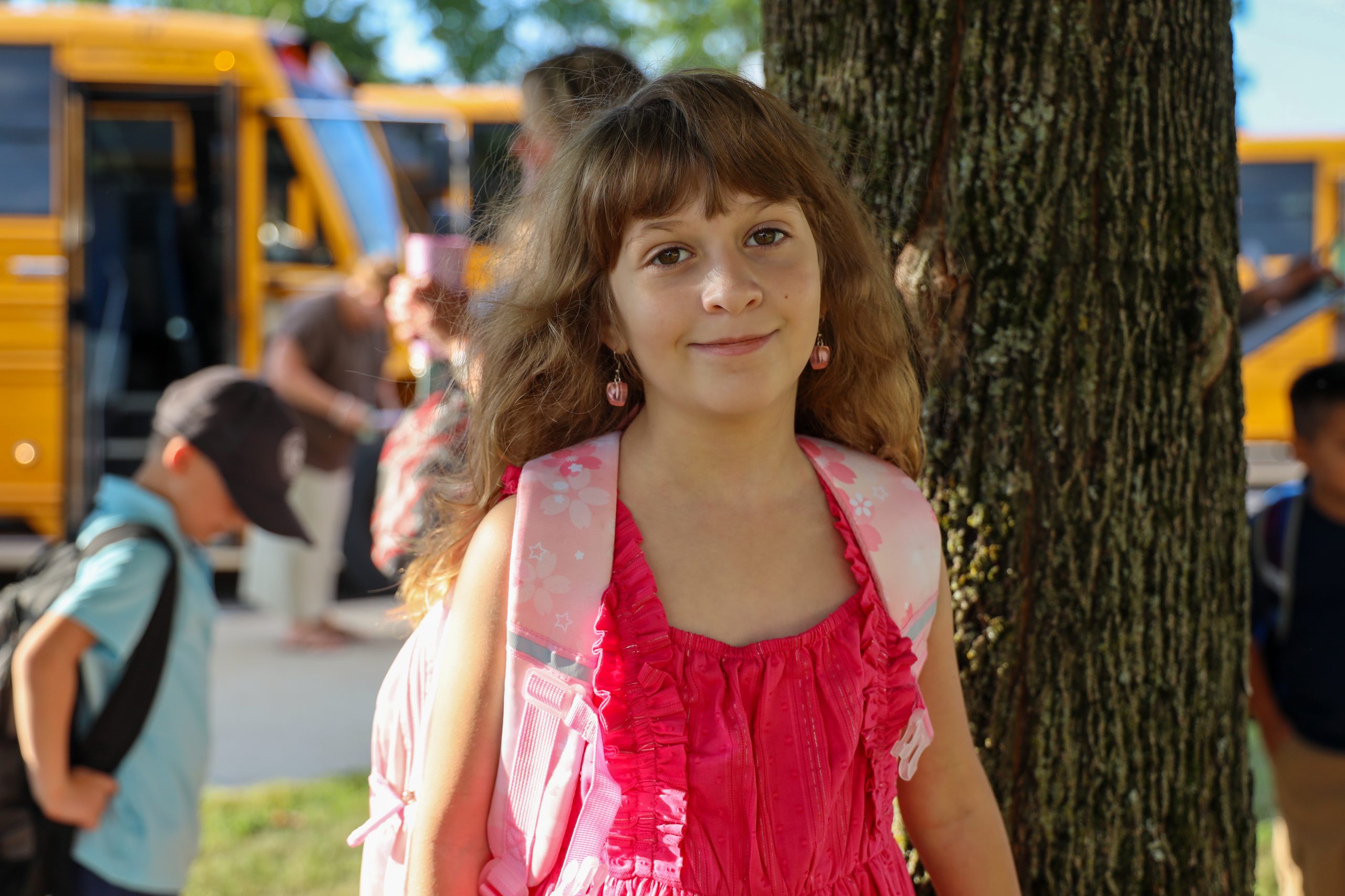 A girl posing for a photograph with buses behind her