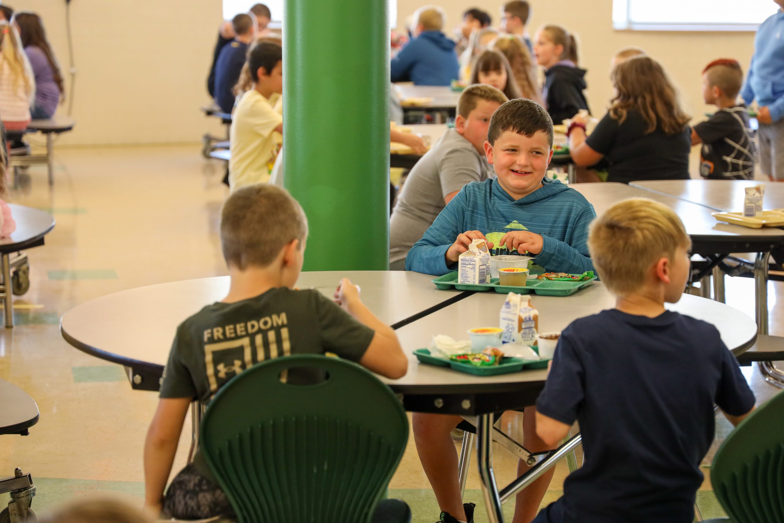 Students sitting at lunch tables with meals in front of them