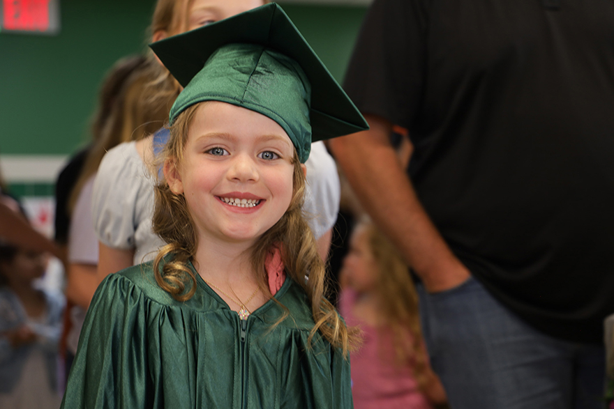 Student wearing green cap and gown.