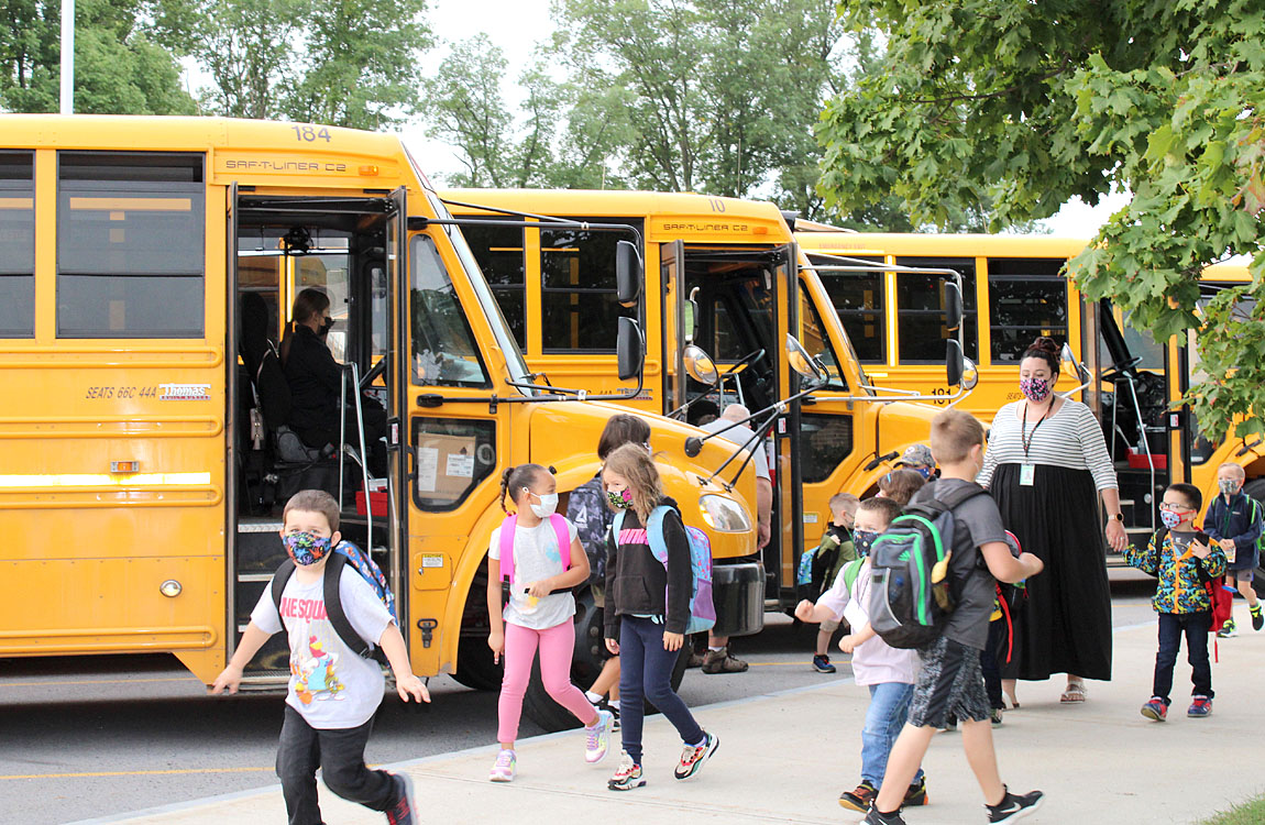 students exit buses as they arrive for school