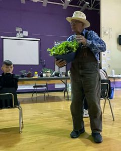 Farmer holds plant in front of student