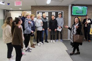Group of students standing in hallway speaking with adult
