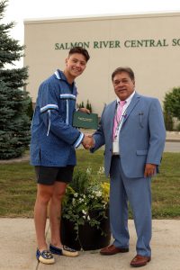 Image showing student shaking hands with administrator while holding up a diploma