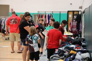 Image of several people, including children, standing near racks of clothing