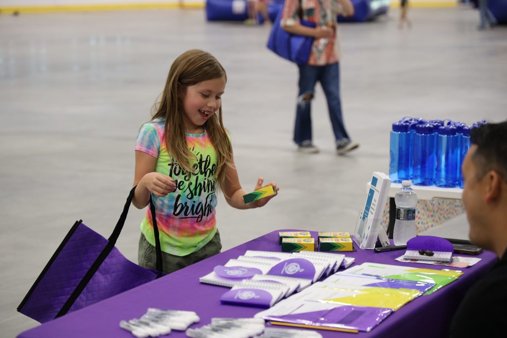 Image of young child picking up box of crayons off of a table