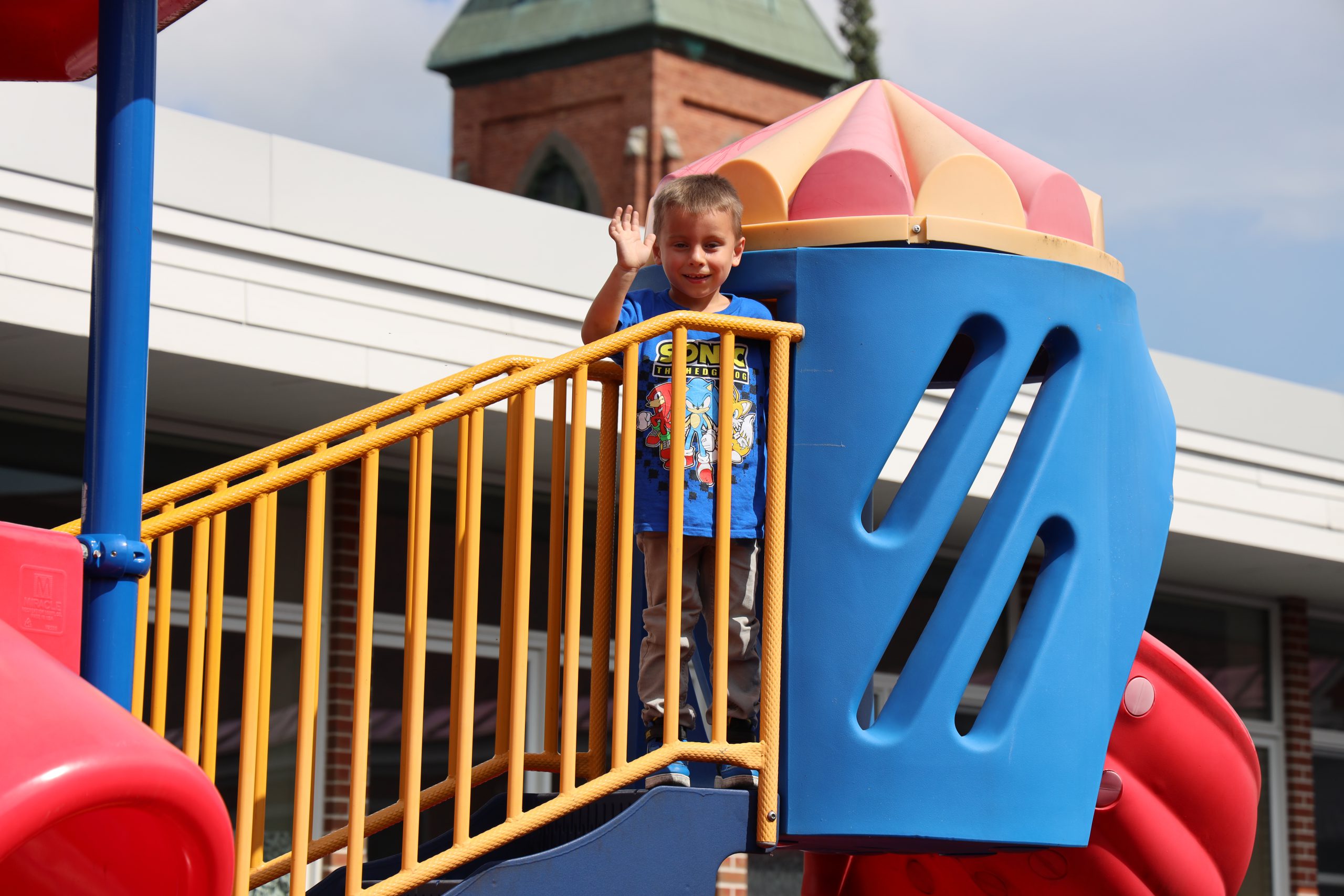 Image of student on playground waving