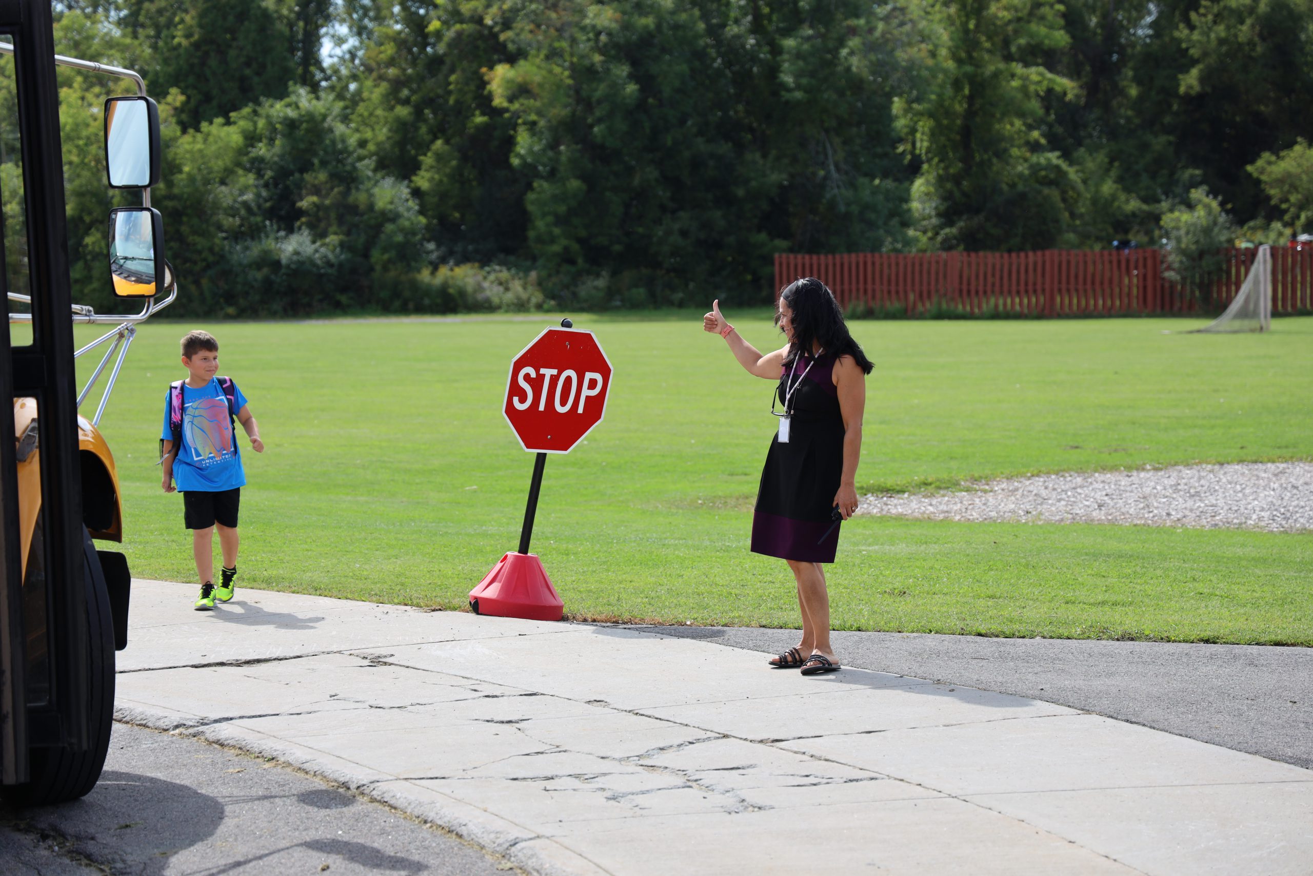 Image of staff member welcoming student off bus