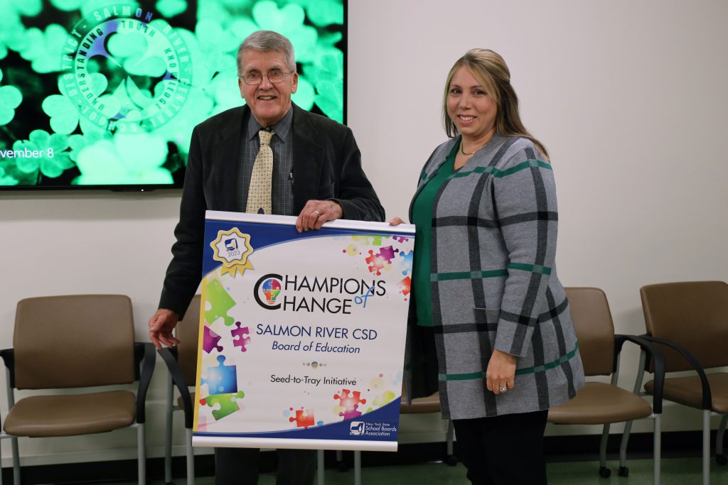 Image of two people holding up a banner that says 'Champions of Change'