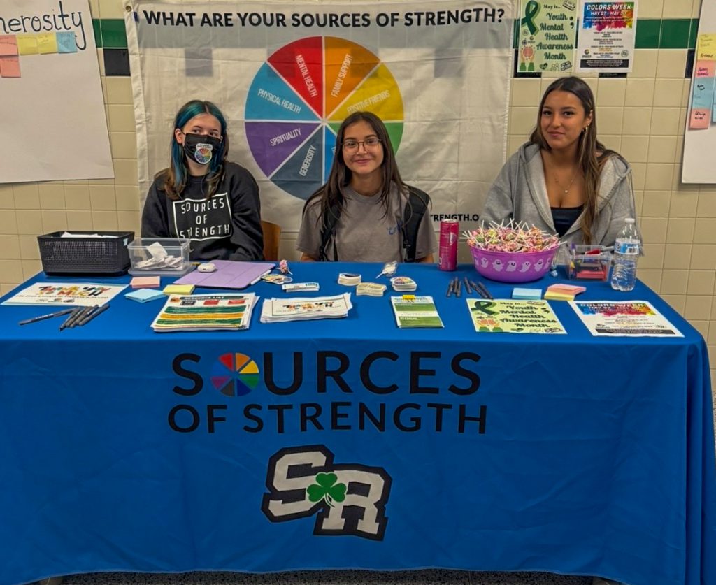 Three students sitting at a table with words that say 'Sources of Strength SR'