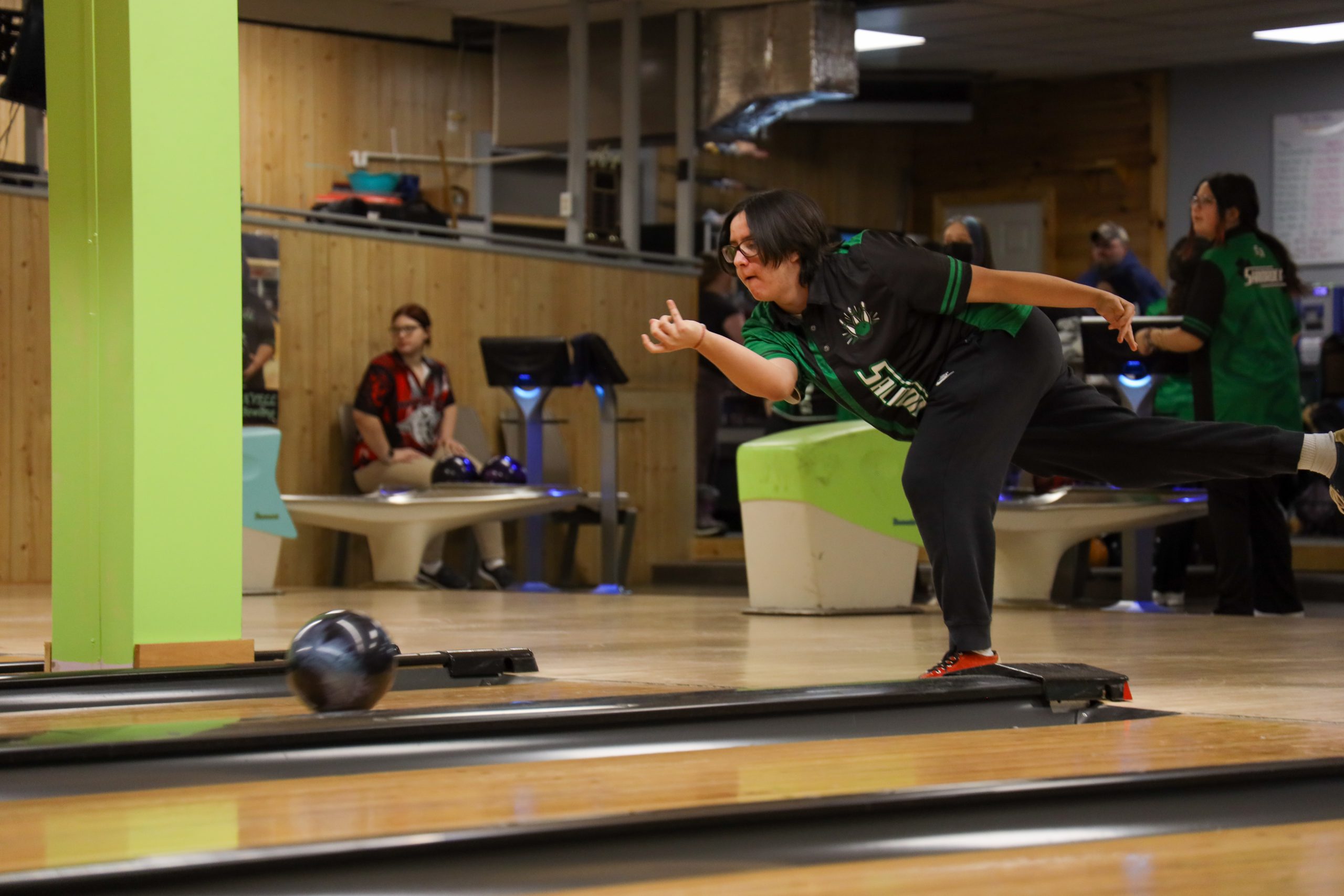 A student bowls in a bowling alley