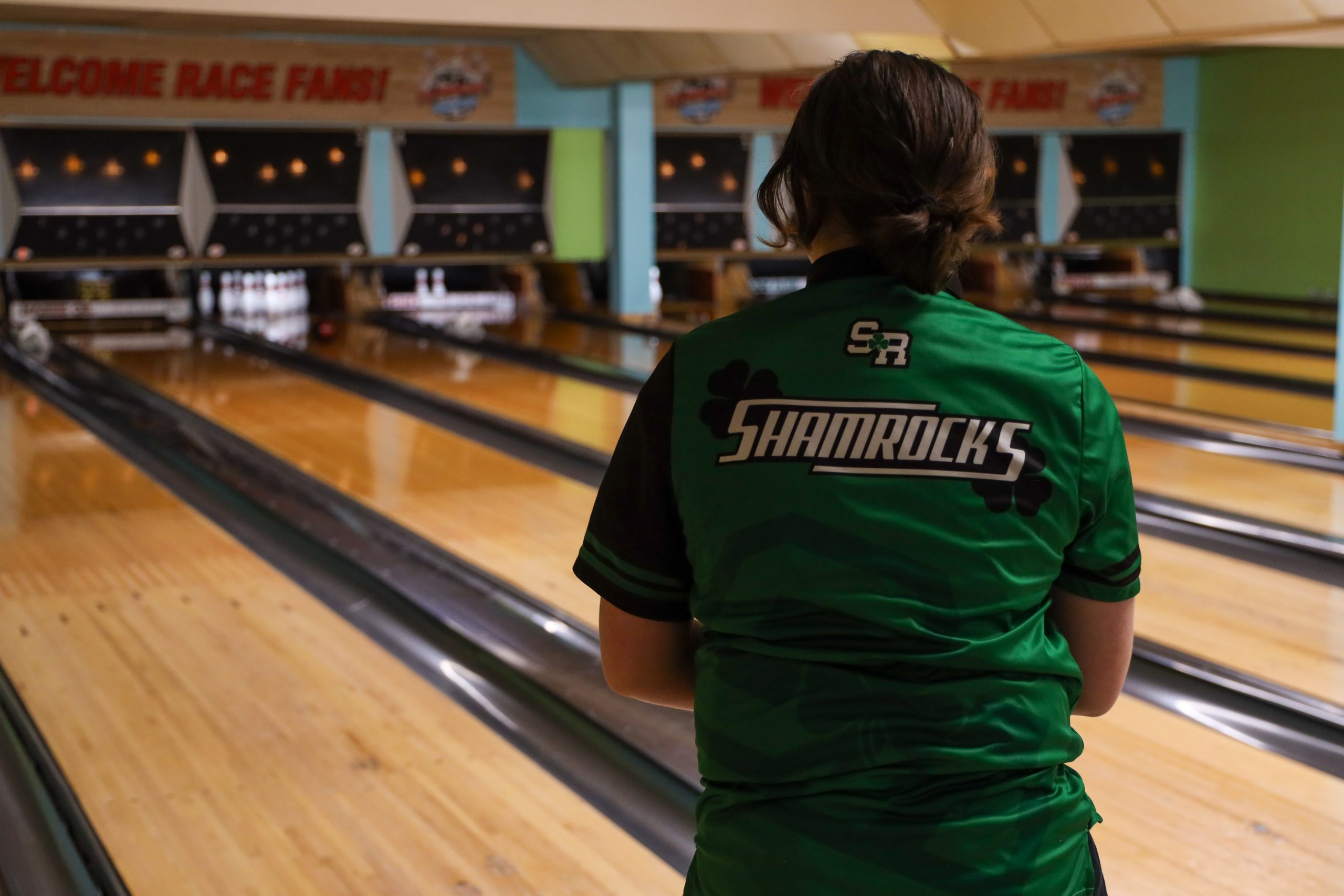 A person wearing a 'Shamrocks' uniform while in a bowling alley